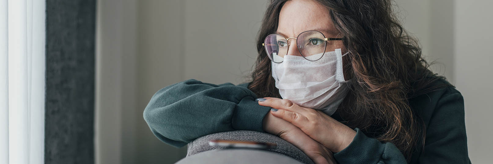 woman in a mask sitting on her sofa at home